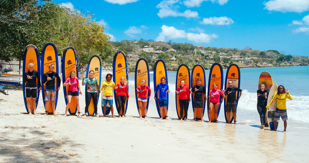 A group of surfer girls in the beach having surf lessons