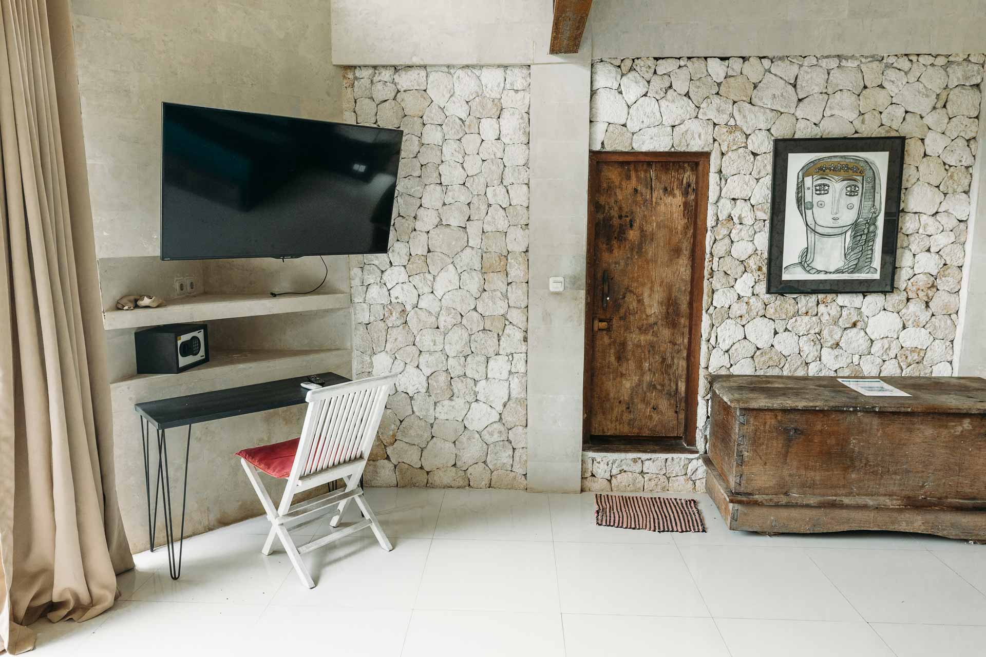 A hotel room with stone walls with a working desk and TV