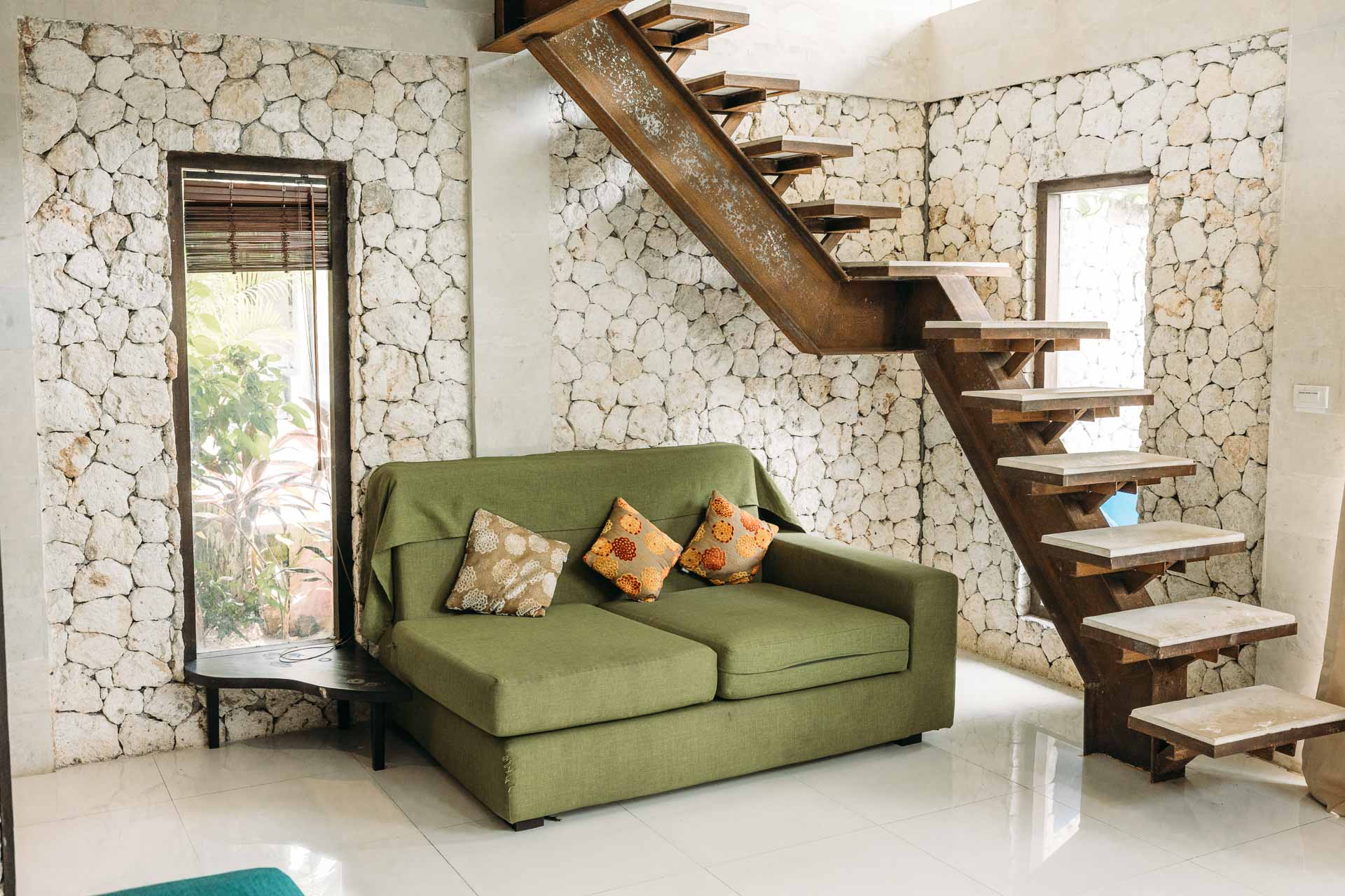 A room in hotel with stones for walls and green sofa