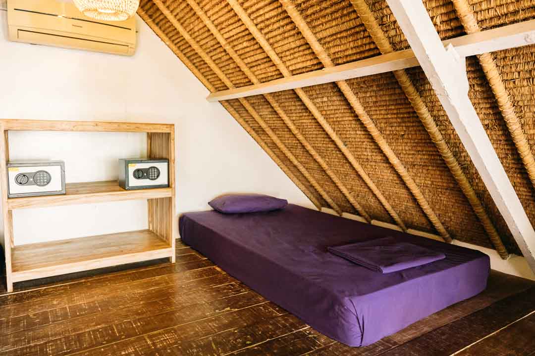 single bed with pillow and purple bedding in javanese roofed room