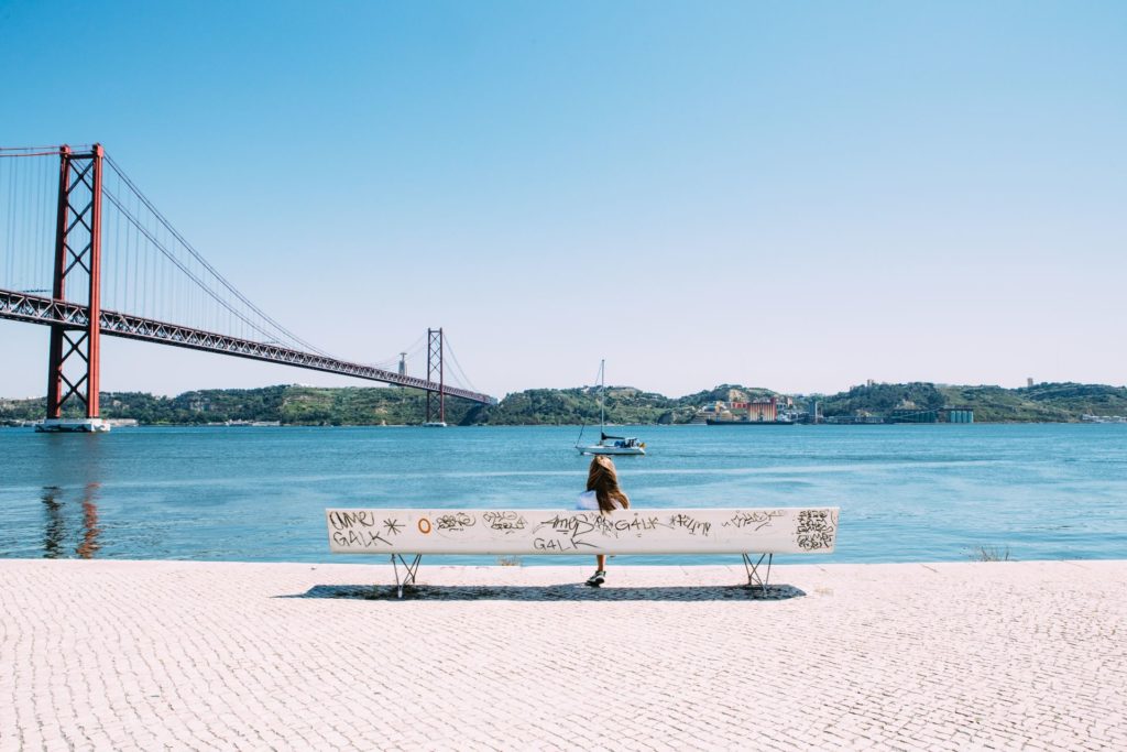 Girl sitting on bench staring out over the Tagus River in Portugal