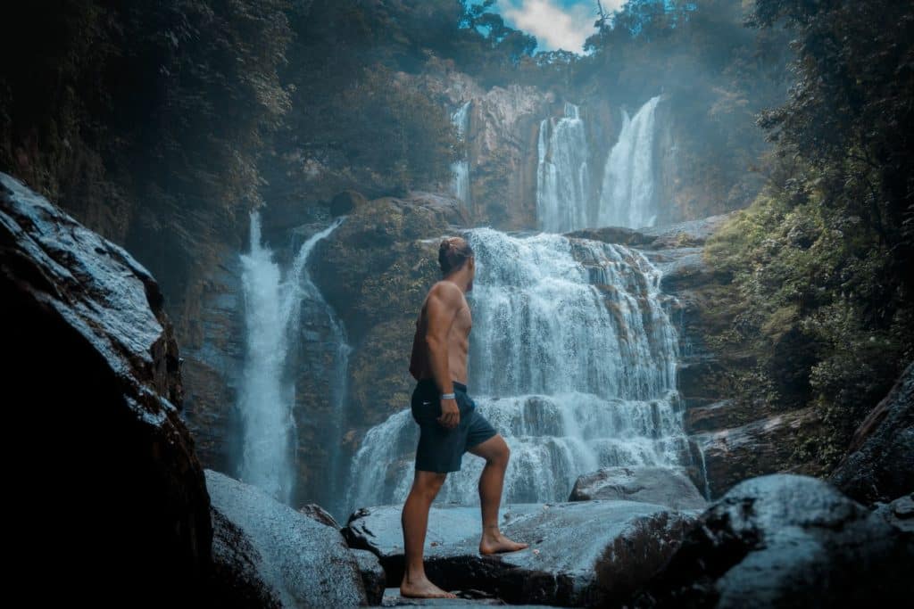 Mann steht vor einem Wasserfall