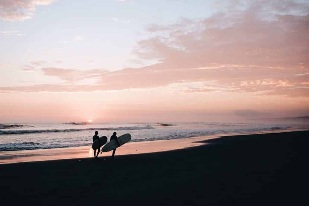 Surf instructor walks with a pupil up the beach