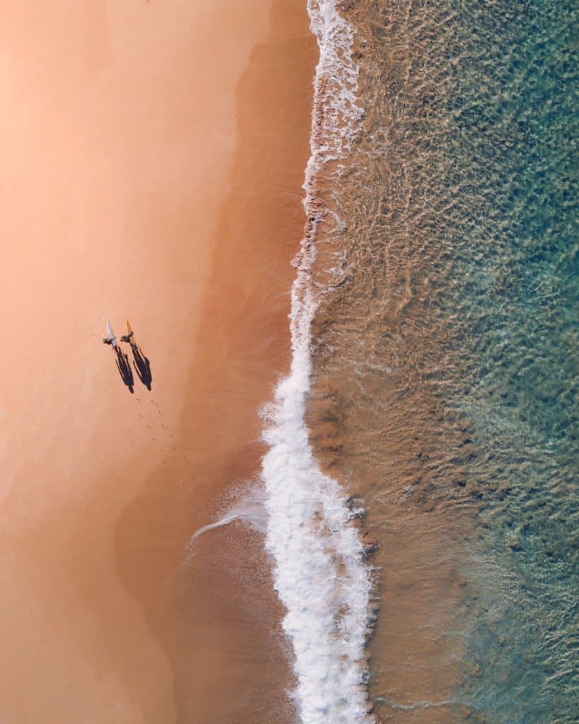 Two surfers walking down beach