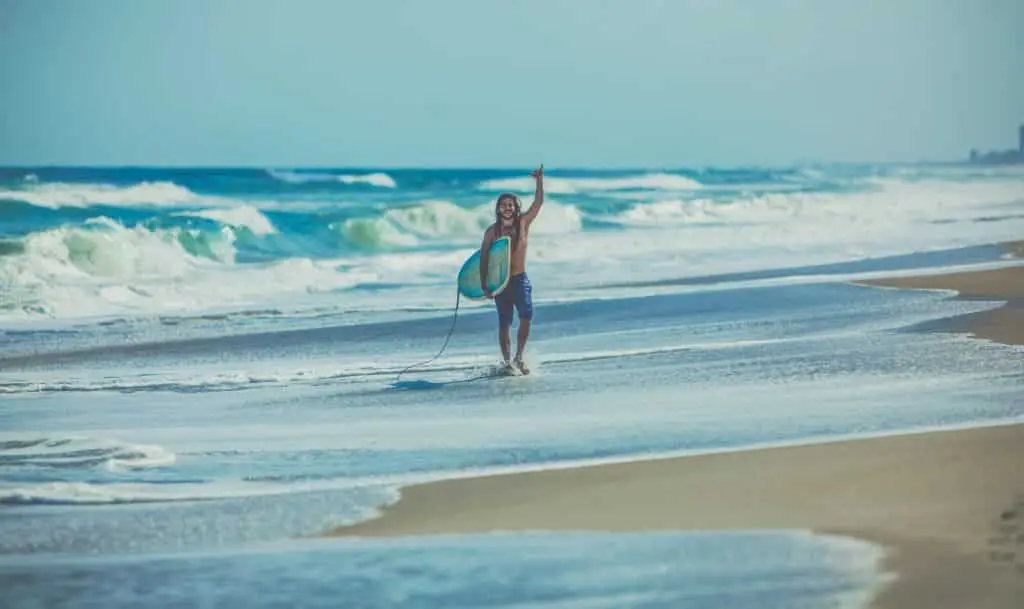 Happy surfer walking down the beach