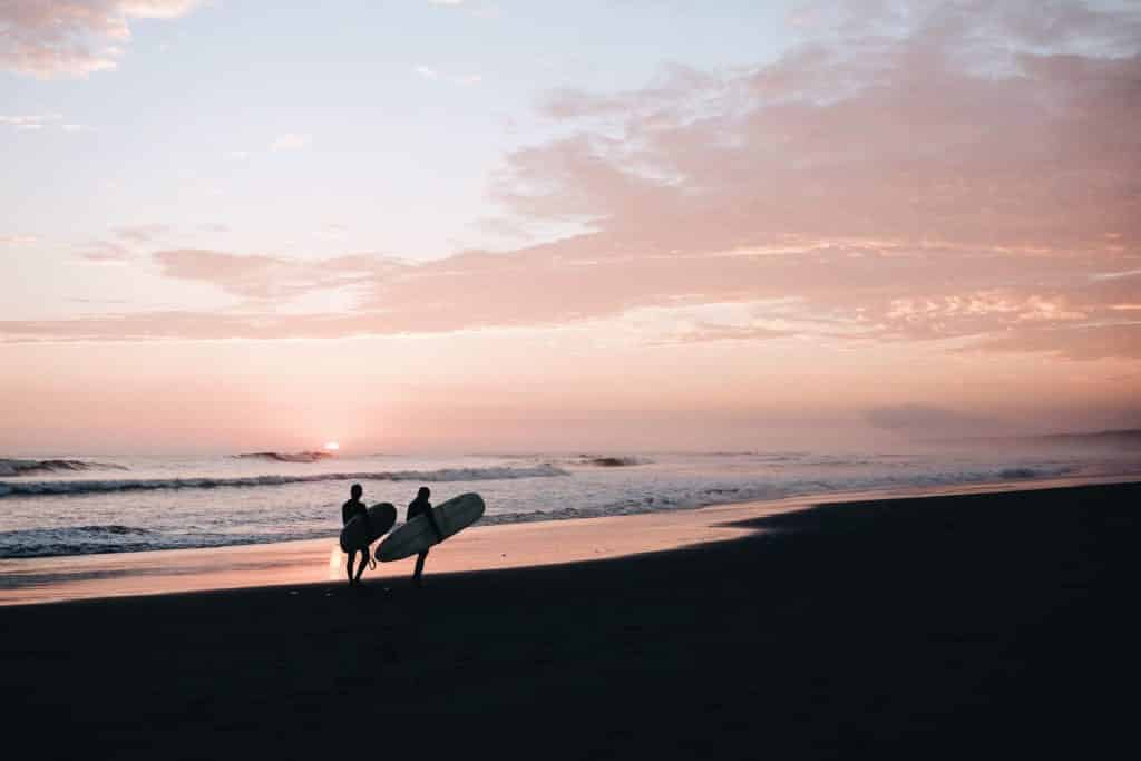 Two people walking along beach after a surf lesson