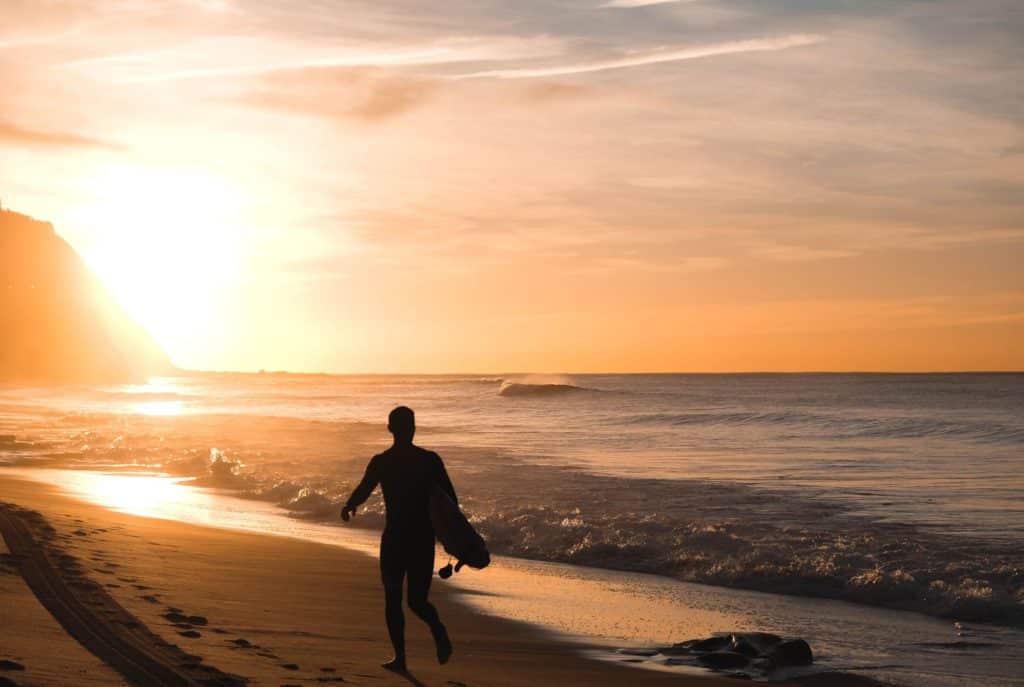 Man running down beach at sunrise