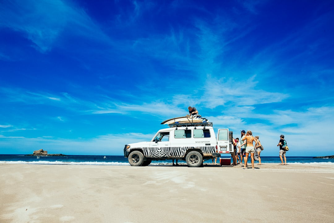 A group of surfers arriving with jeep at beach