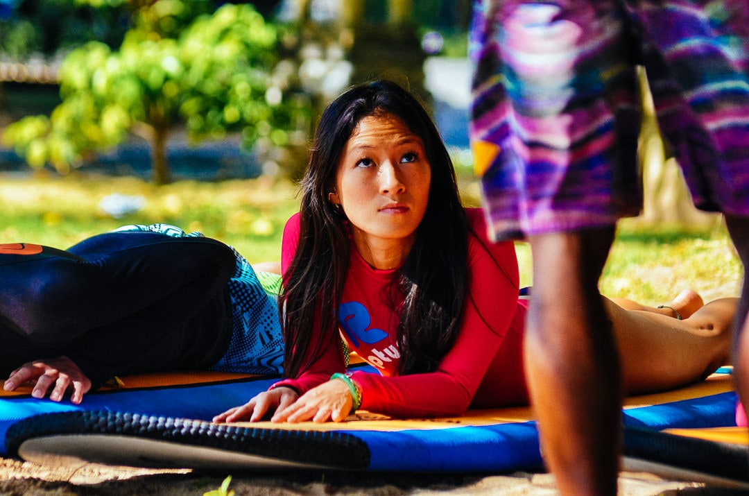 Surfer girl paying attention to surf instructor lesson