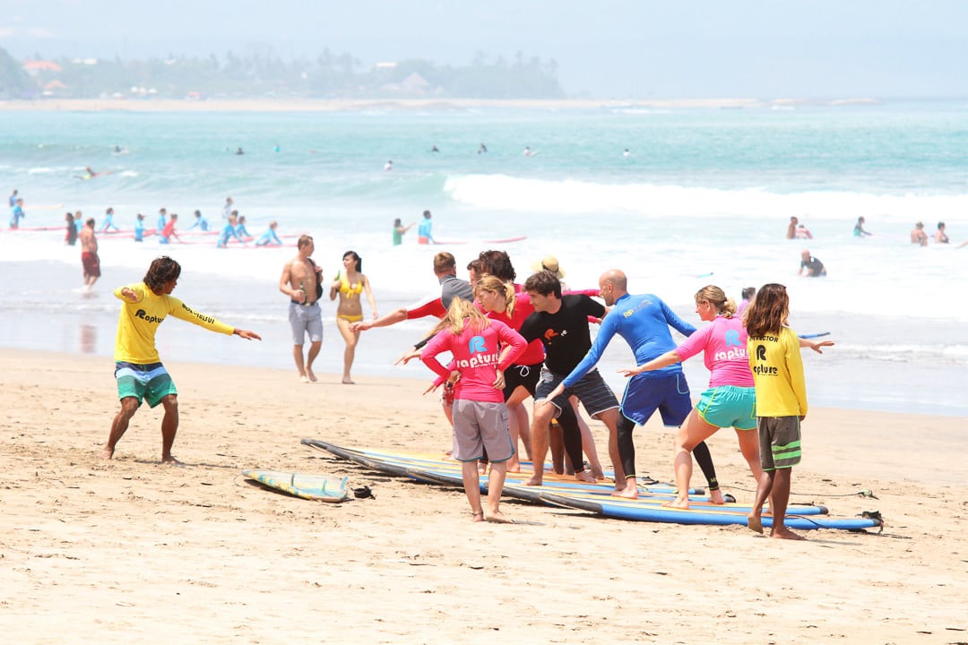 A group of surfers standing up on surfboard in the shore