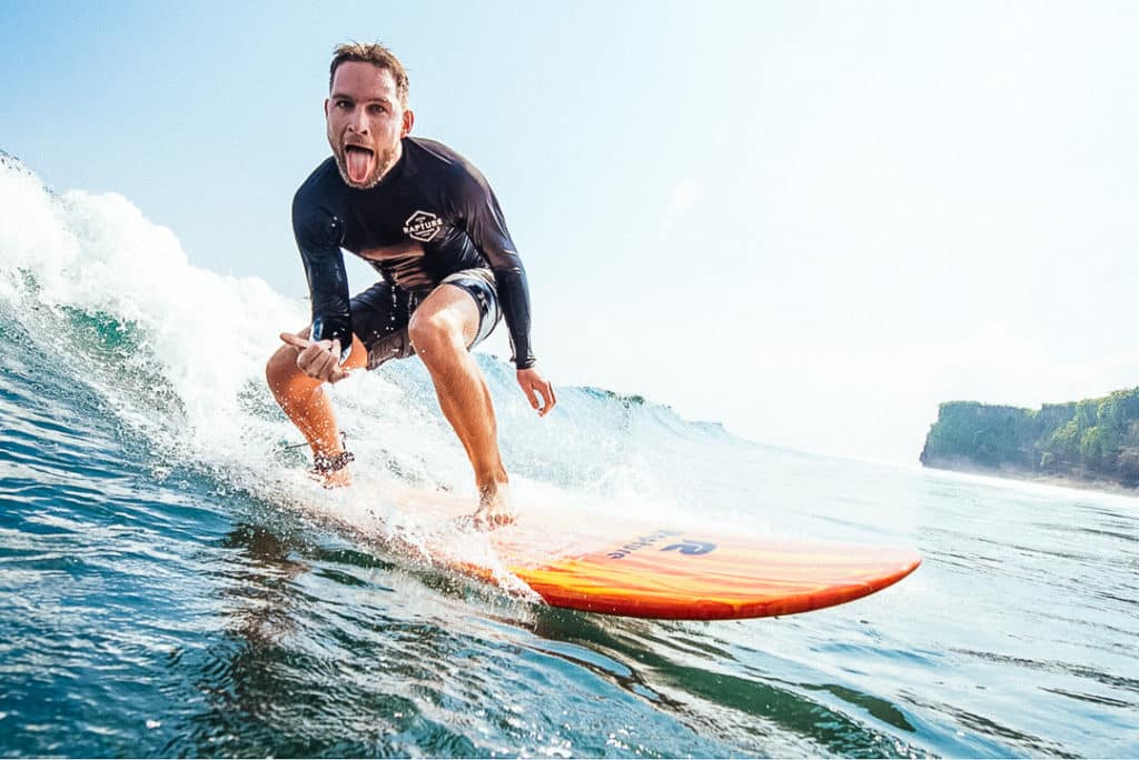 Ein glücklicher Surfer reitet auf einer Welle am Strand von Bali