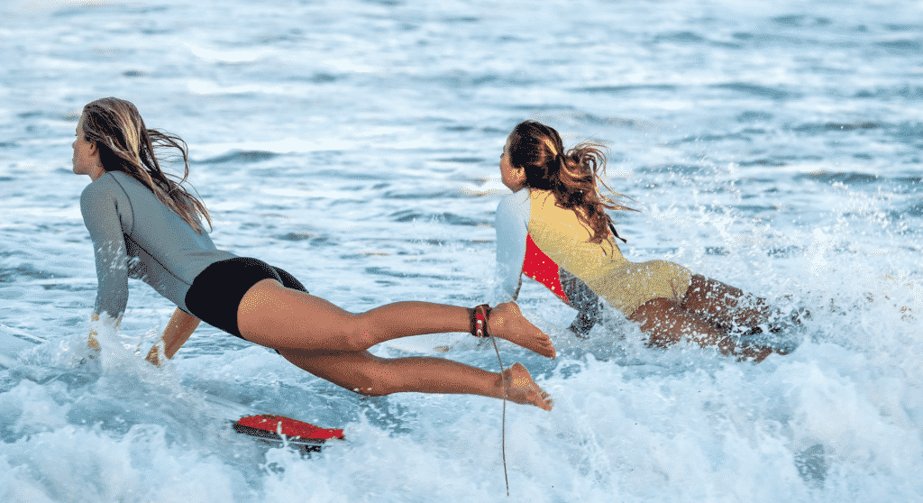 Female surfers in Portugal jumping into the waves