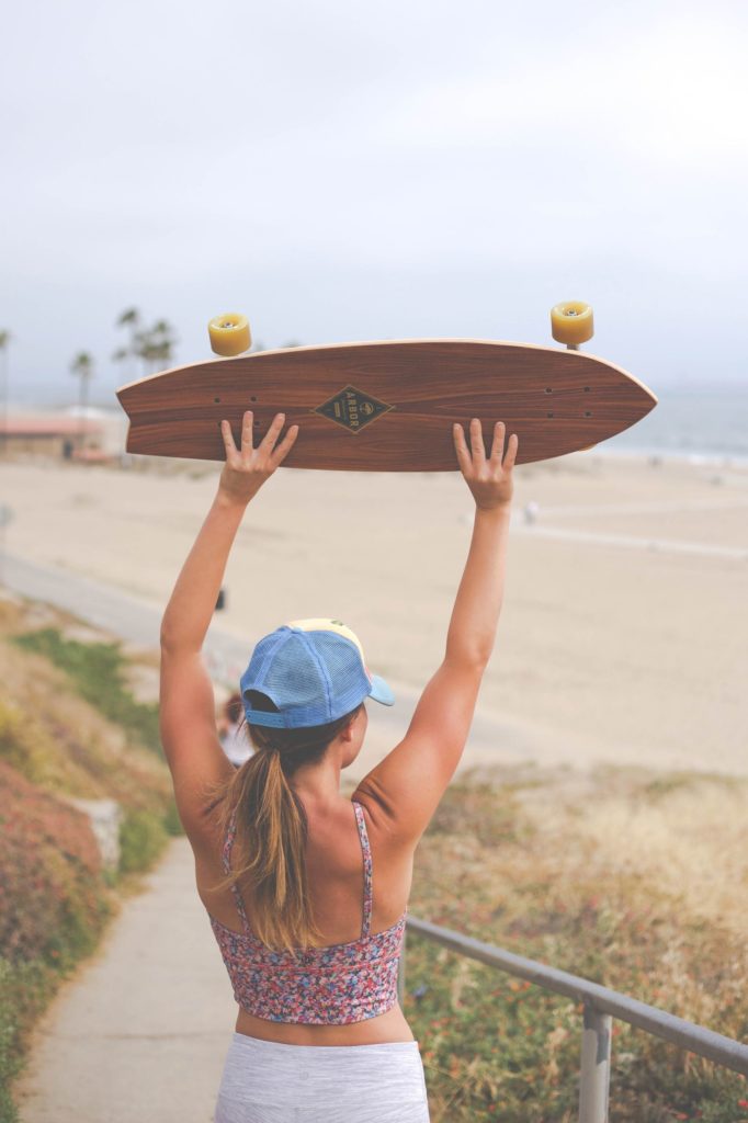 Girl holding a skateboard above her head