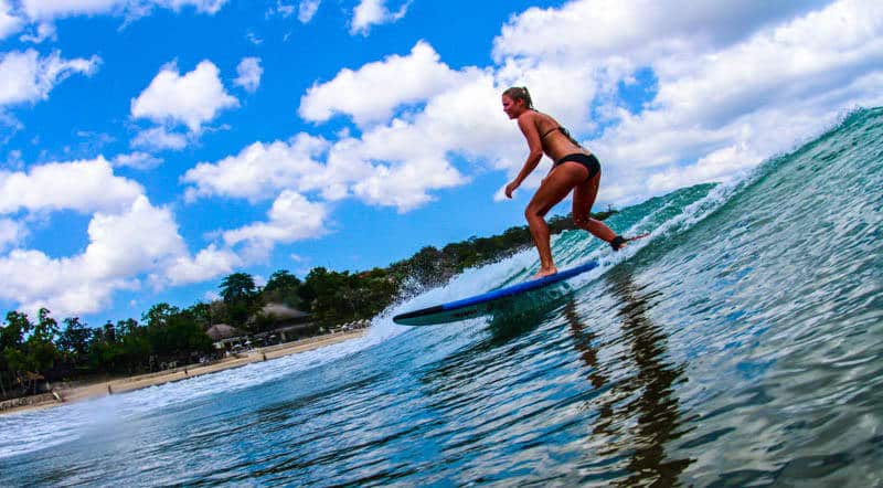 Girl standing up on a mini-Malibu surfboard