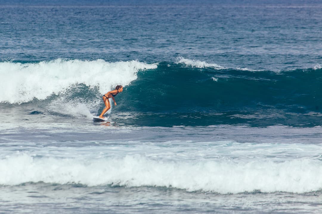 Ein Surfer-Mädchen reitet auf einer Welle in Canggu