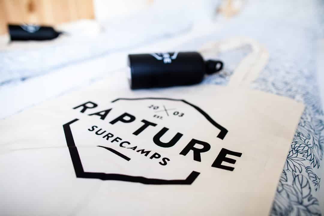 Rapturecamps tote bag and water bottle on a bed
