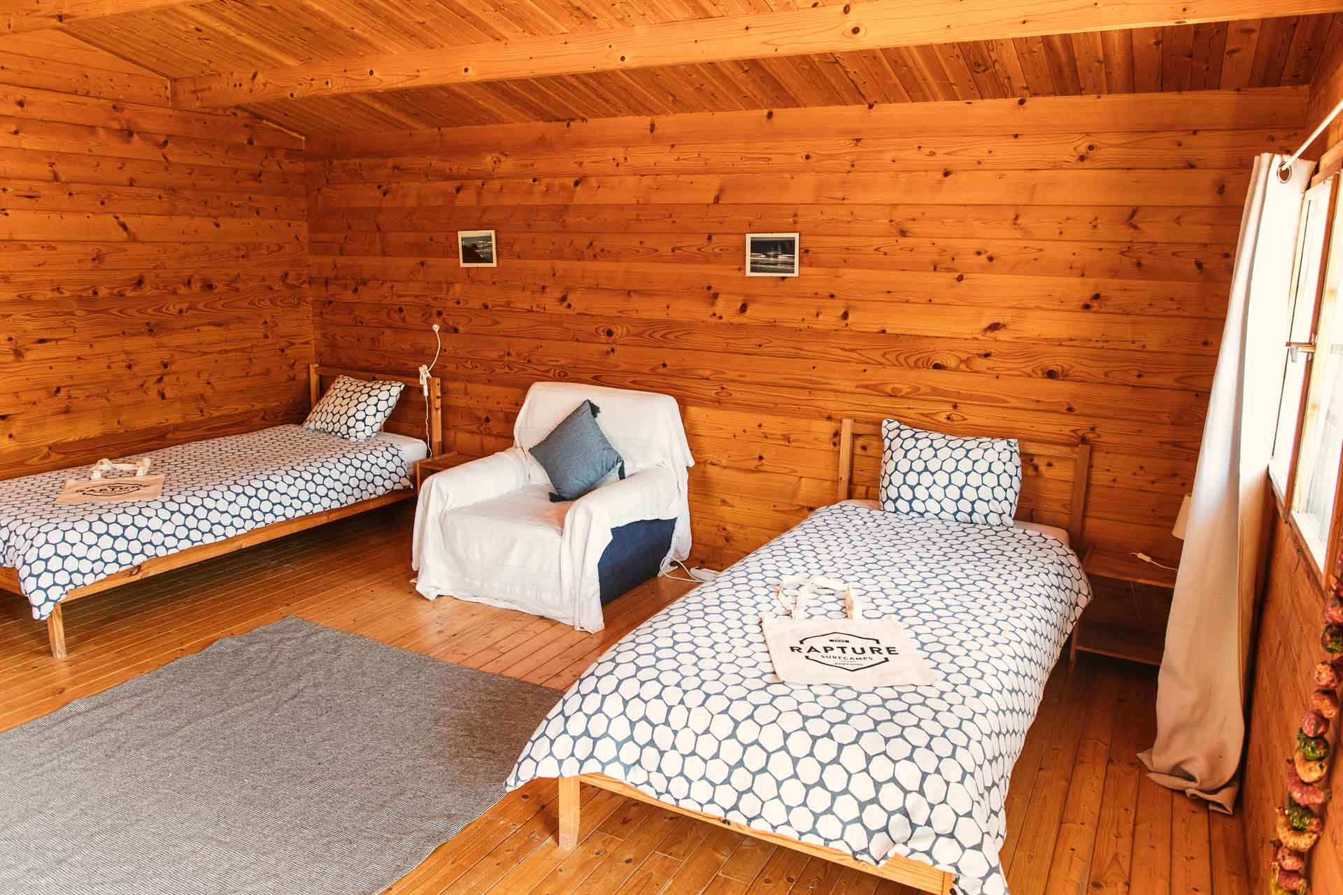 2 single beds and a sofa with rustic deco in a surfcamp