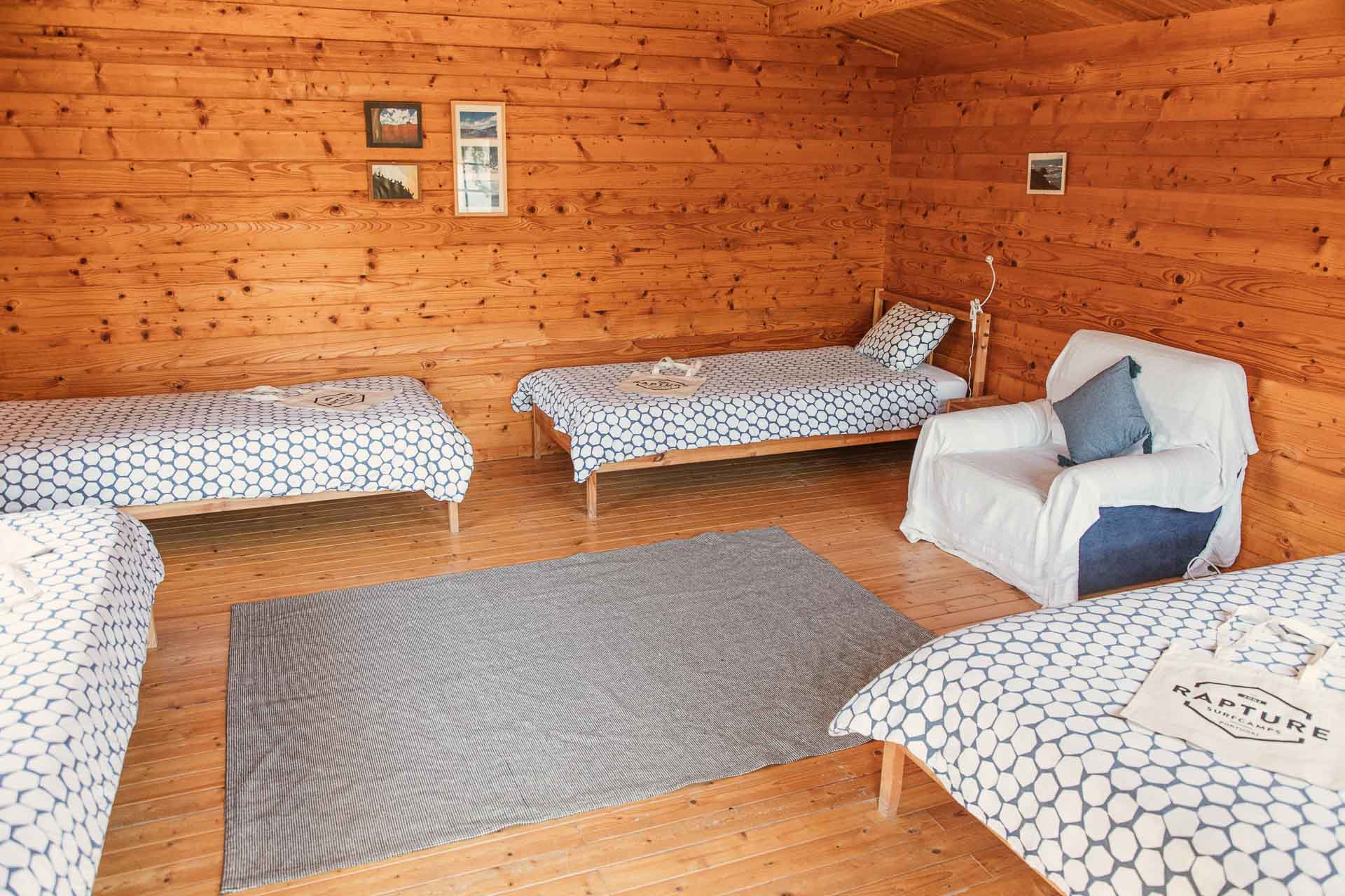 4 single beds and a sofa in a shared room of a rustic surfcamp