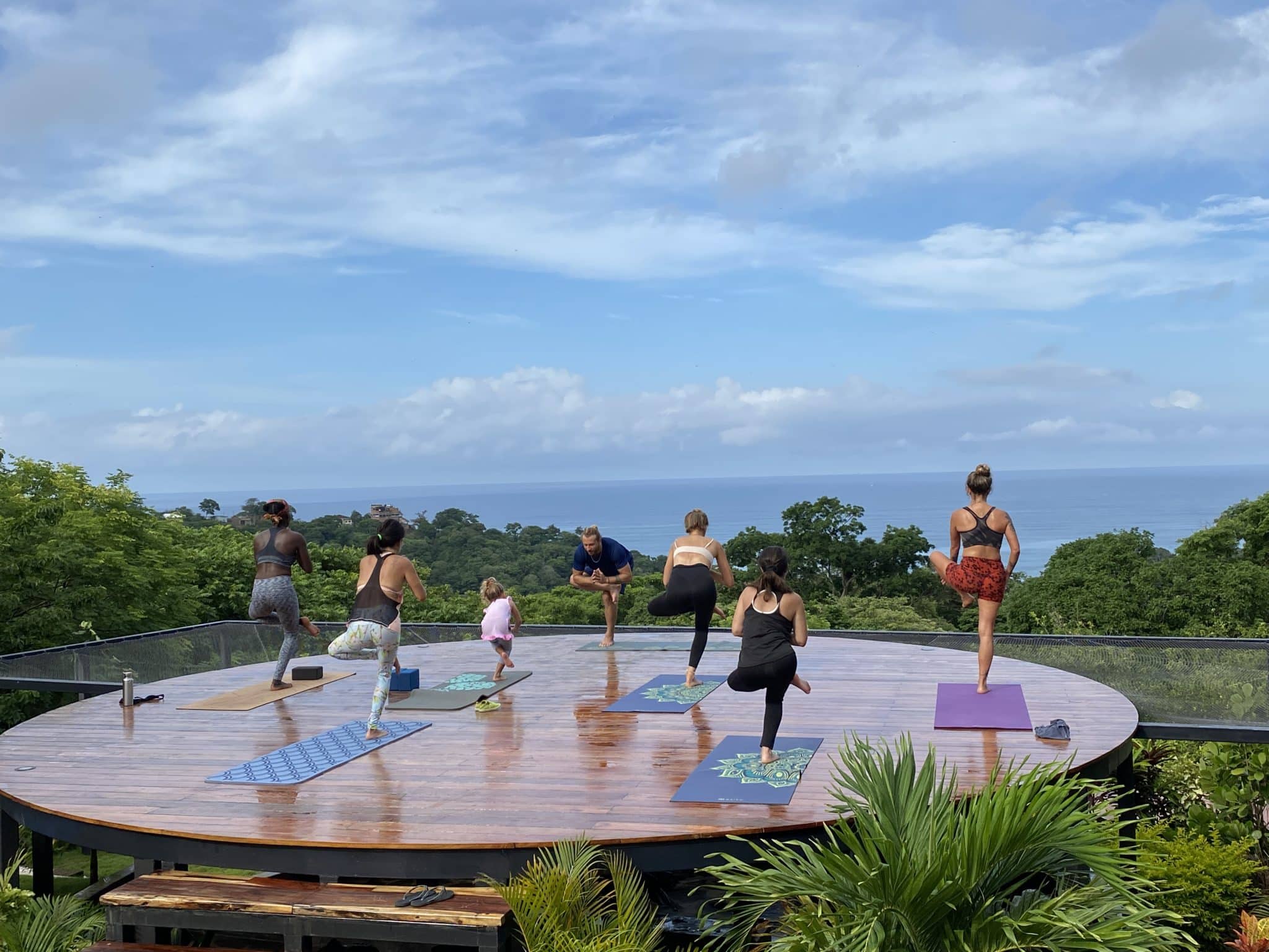 A group of people practising yoga on a round deck with view