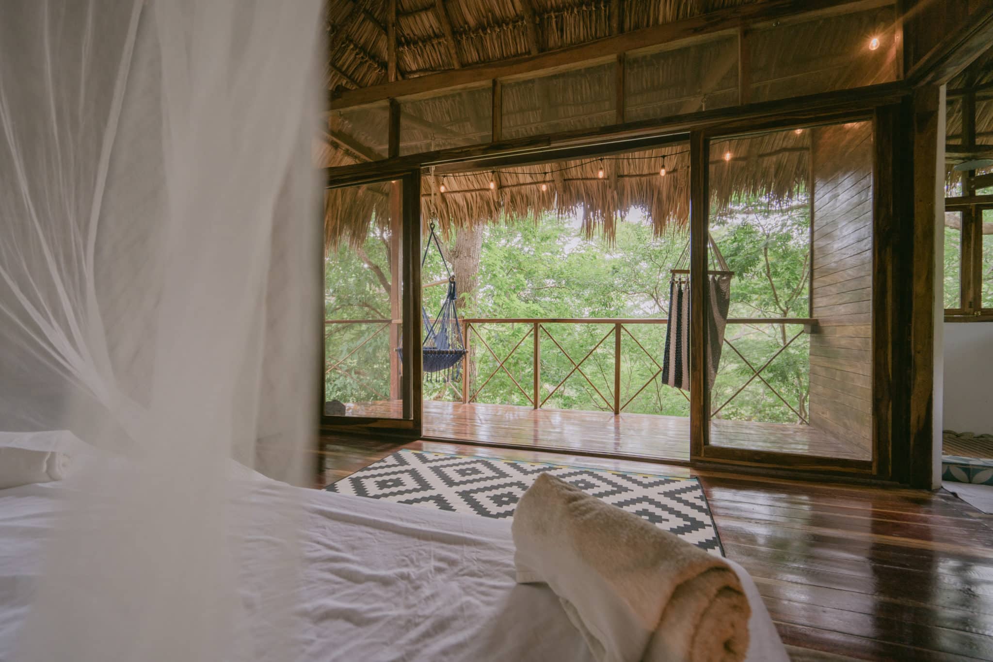 A bed with mosquito net on the cabana room in Rapture Surf resort