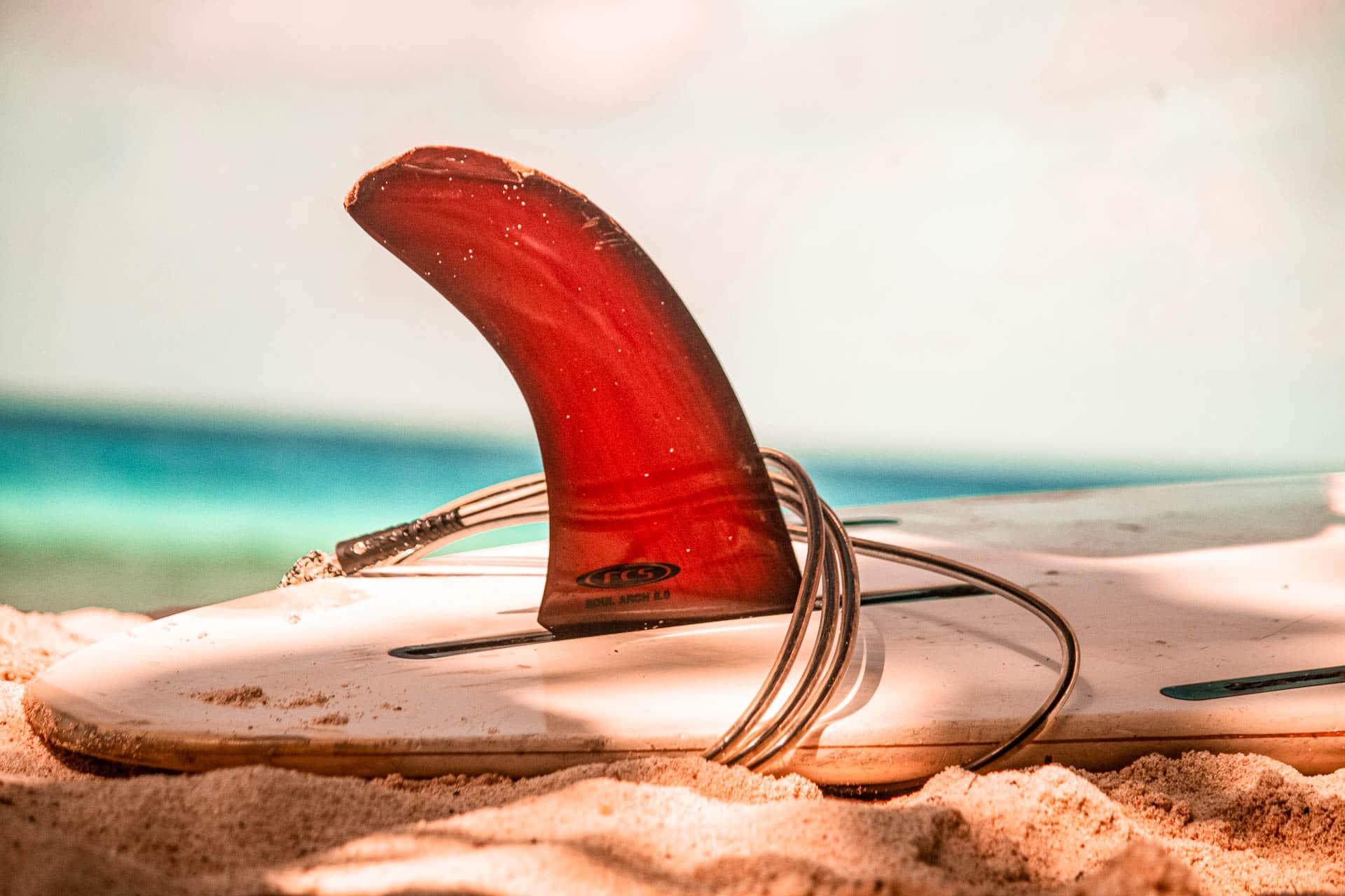 Closeup of a Surfboard with Red Fin on the Beach