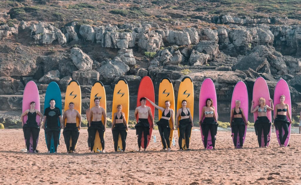A group of surfers posing on the beach with surfboards behind them_background