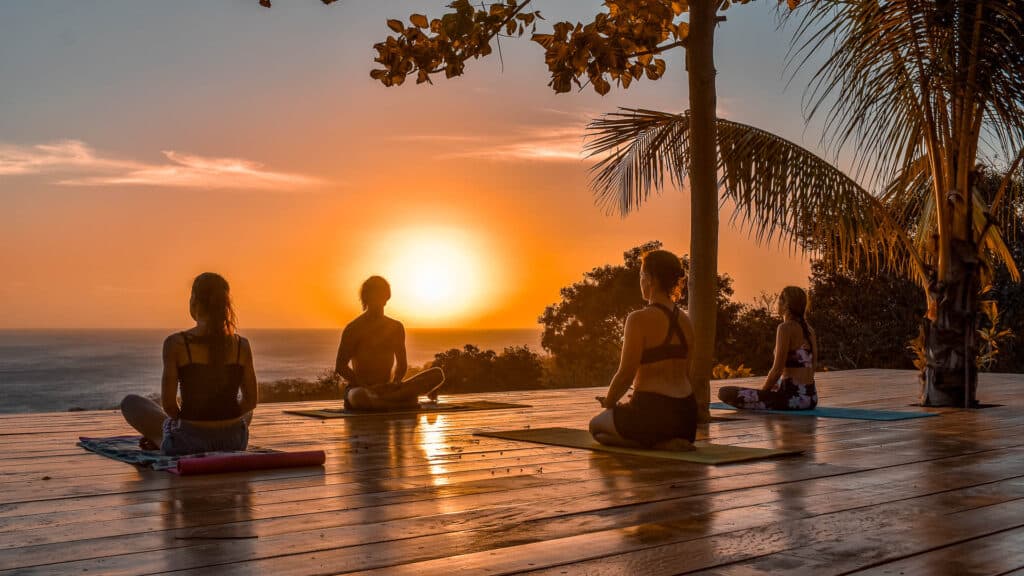 A group of surfers practicing yoga at Rapture Surfcamps at sunset